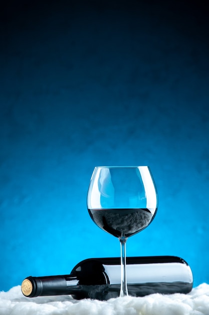Verre à vin vue de face et bouteille horizontale sur fond bleu