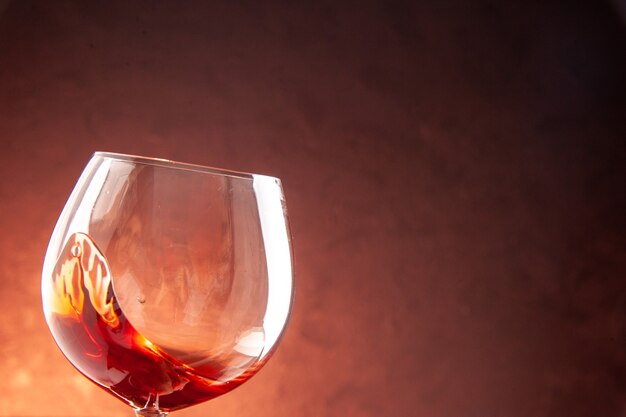 Verre à vin vue de face avec peu de vin à l'intérieur sur une boisson alcoolisée au champagne de couleur sombre