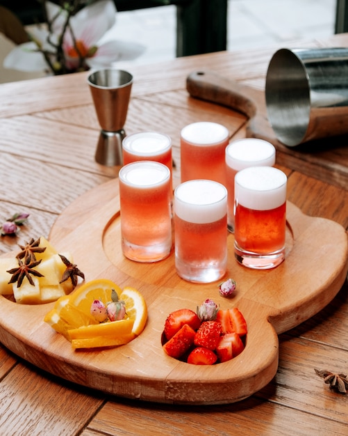 Photo gratuite verres de bière avec mousse et fruits en tranches sur la planche