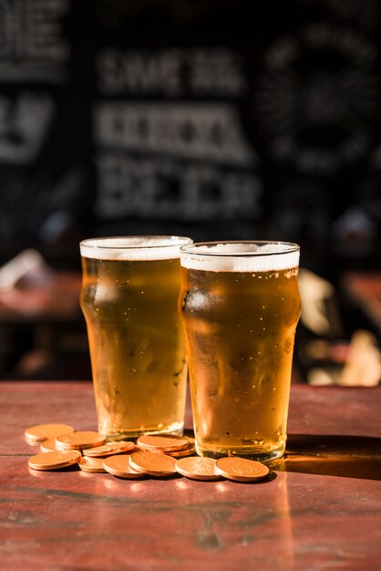 Verres de boisson près de tas de pièces à table