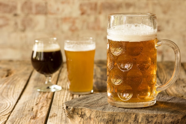 Verres de différents types de bière brune et légère sur table en bois