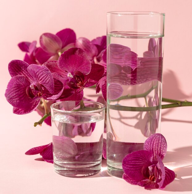 Verres avec de l'eau à côté de fleurs