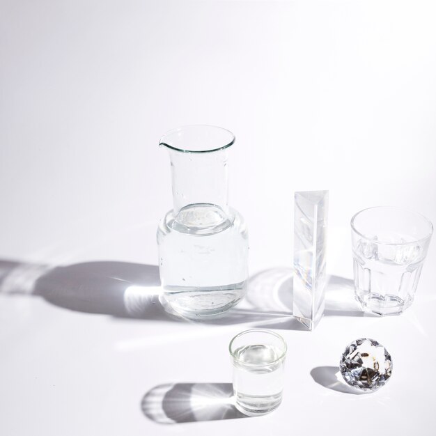 Verres à eau; prisme; diamant mousseux et bécher avec ombre sur fond blanc