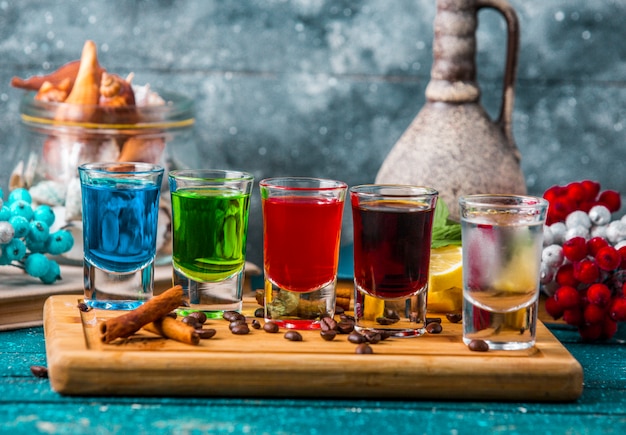 verres à liqueur avec boissons colorées sur planche de bois