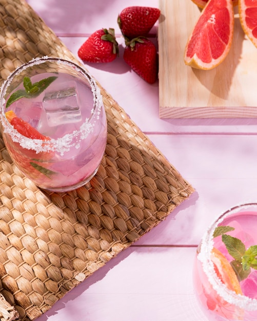 Photo gratuite verres avec pamplemousse et boisson aux fraises sur table