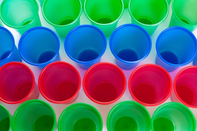 Verres en plastique multicolores isolés sur fond blanc