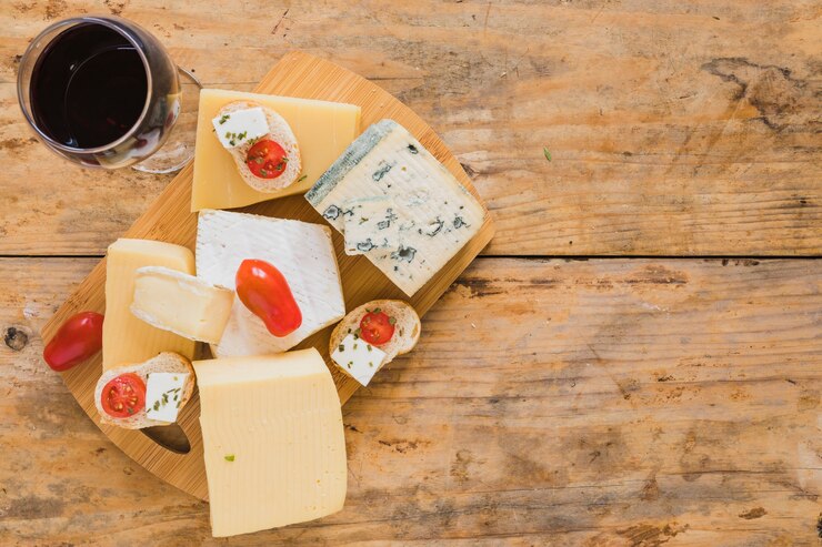 Photo gratuit verres à vin avec des raisins et une variété de blocs de fromage sur le bureau en bois