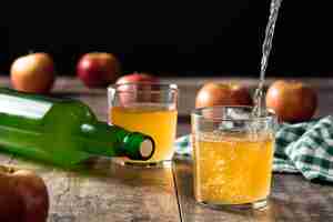 Photo gratuite verser la boisson au cidre de pomme dans un verre sur une table en bois