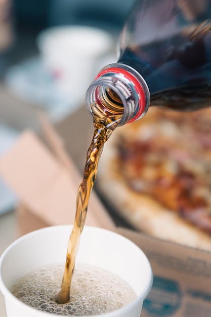 Photo gratuite verser une boisson gazeuse de la bouteille au verre en gros plan