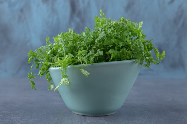 Verts nouvellement récoltés dans un bol, sur la surface en marbre.