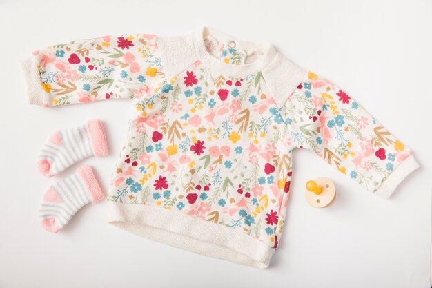 Vêtements de bébé et chaussettes avec sucette isolé sur fond blanc