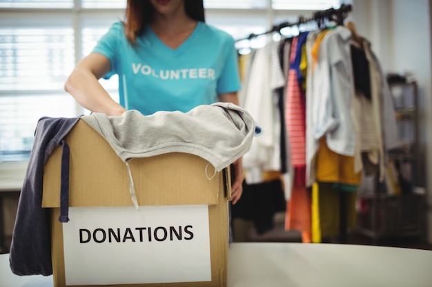 Photo gratuite les vêtements féminins bénévoles tenant en boîte de dons