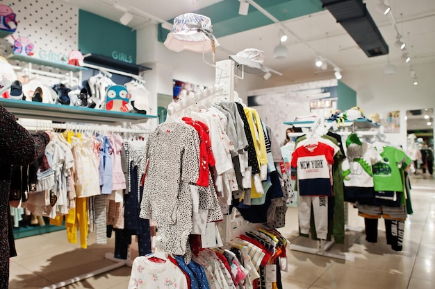 Des vêtements lumineux pour enfants sont accrochés à l'écran du magasin de vêtements pour bébés