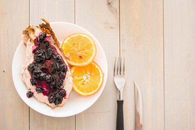 Viande avec de la confiture près des oranges sur une assiette