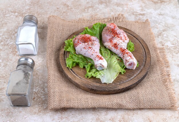 Viande de cuisses de poulet non cuites aux légumes sur une planche de bois