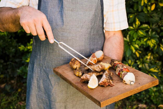 Viande grillée et légumes savoureux sur un bureau en bois dans les mains