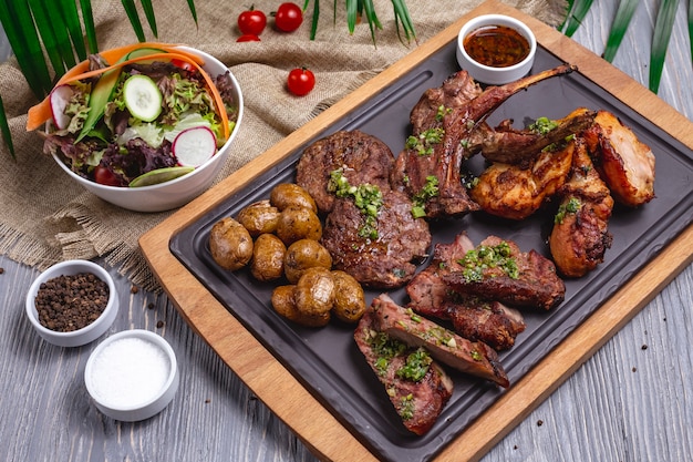 Viande grillée mixte côtes d'agneau poulet pomme de terre vue latérale