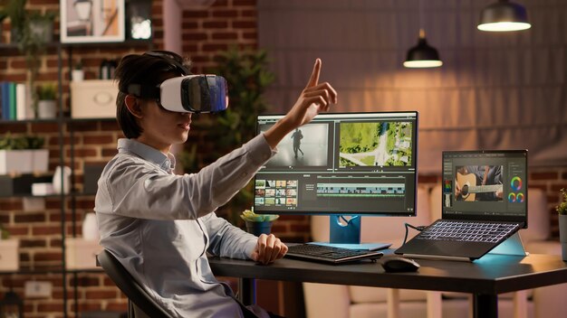 Vidéaste utilisant un logiciel d'édition et des lunettes vr pour concevoir un montage pour la production de films. Montez des séquences de films avec des effets visuels sur ordinateur, en travaillant avec des lunettes de réalité virtuelle.