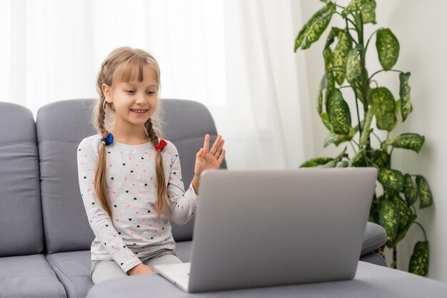 Une vidéoconférence de fille avec une enseignante heureuse sur un ordinateur portable