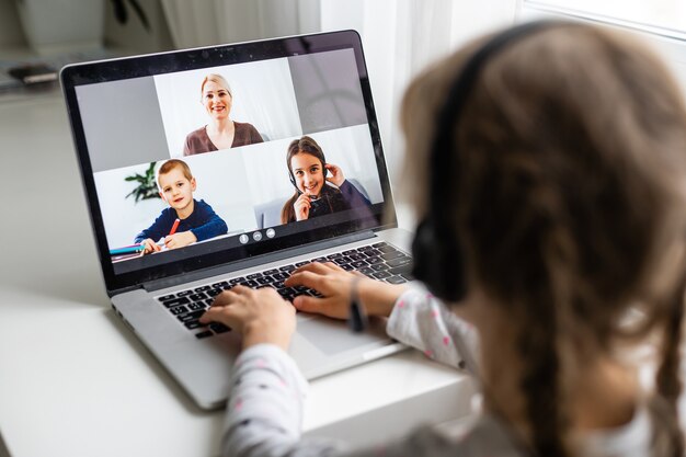 Une vidéoconférence de fille avec une enseignante heureuse sur un ordinateur portable