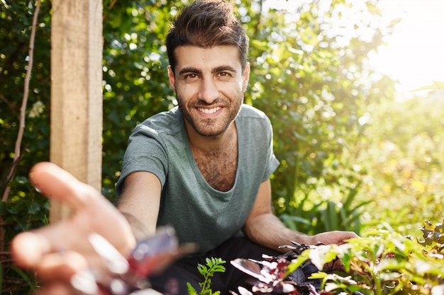 Vie à la campagne, naature. Close up portrait en plein air de jeune homme caucasien barbu attrayant en t-shirt bleu souriant