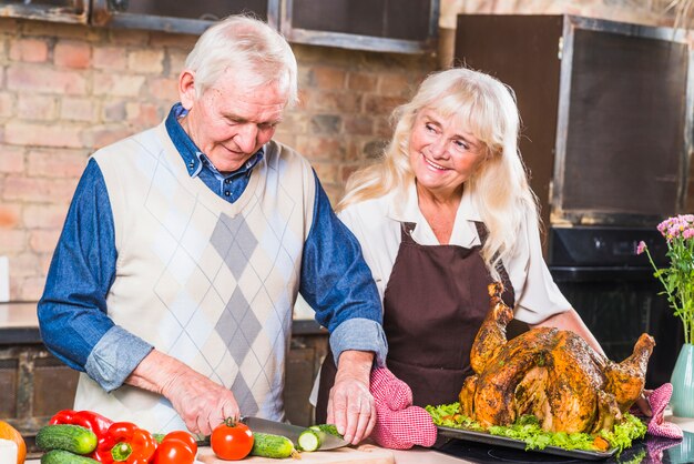 Vieil homme aidant sa femme à cuisiner la dinde