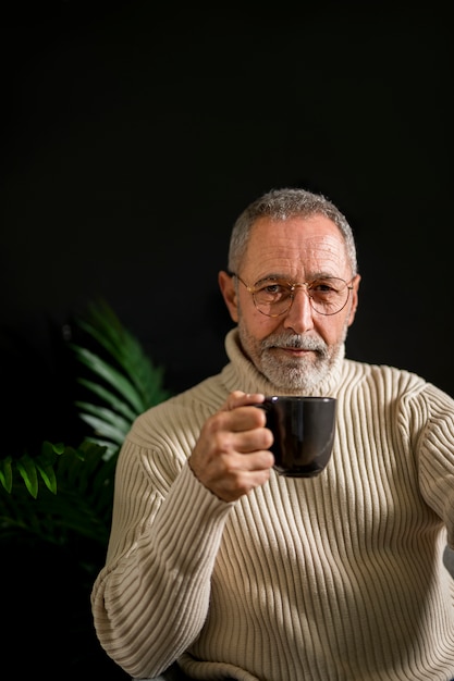 Vieil homme dans des verres avec boisson chaude