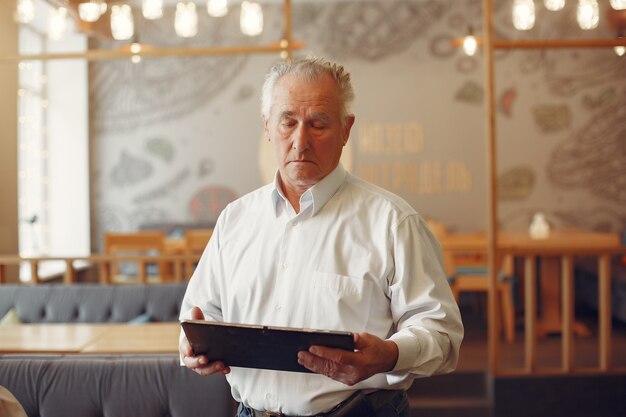 Vieil homme élégant dans un café à l'aide d'un ordinateur portable