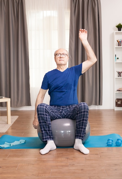 Vieil homme avec une formation de mode de vie sain dans le salon