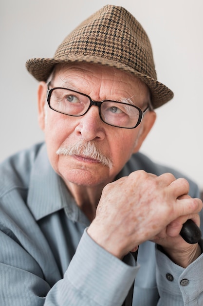 Vieil homme pensif avec des lunettes et une canne