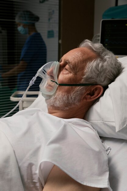 Vieil homme avec respirateur dans un lit d'hôpital