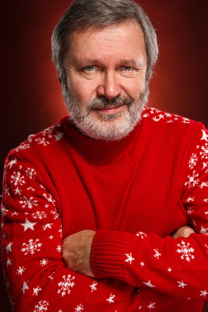 Vieil homme souriant dans un pull de Noël rouge