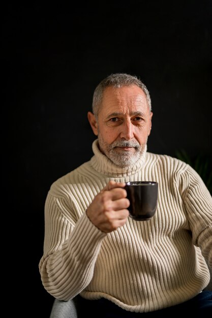 Vieil homme avec une tasse de boisson chaude