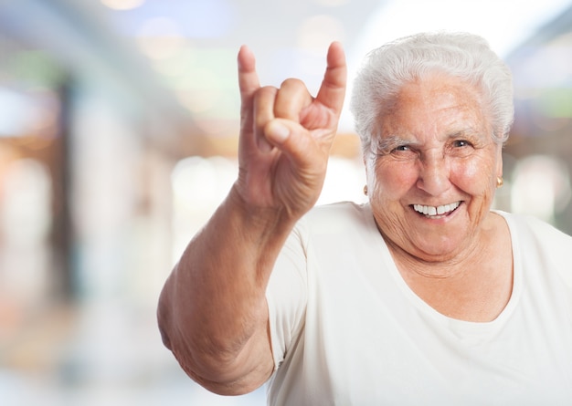 Vieille femme dans un centre commercial faisant les cornes