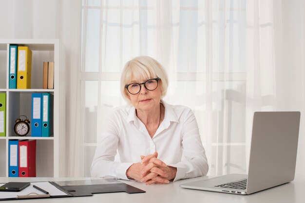 Vieille femme à lunettes assis dans son bureau