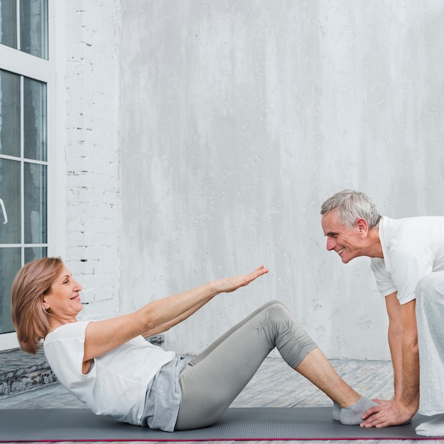 Vieille femme avec son mari faisant des sit ups dans le salon