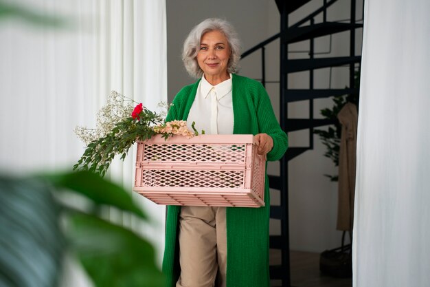 Une vieille femme de taille moyenne s'occupe des plantes.