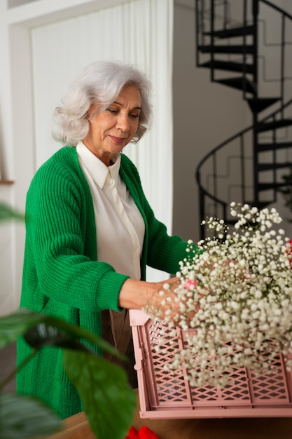 Une vieille femme de taille moyenne s'occupe des plantes.