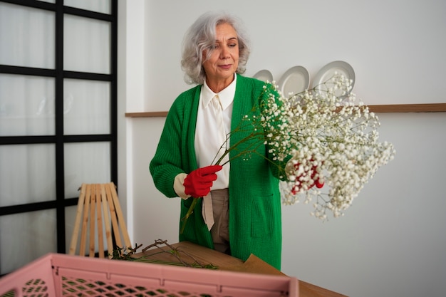 Une vieille femme de taille moyenne s'occupe des plantes.