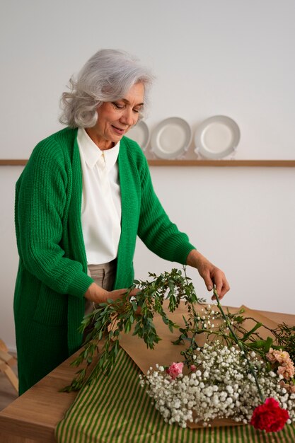 Une vieille femme de taille moyenne s'occupe des plantes.