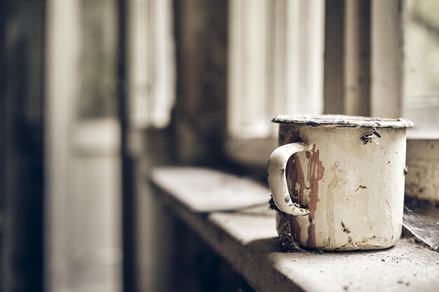 Vieille tasse en métal rouillée dans une vieille pièce poussiéreuse