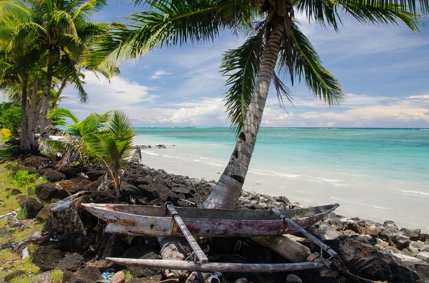 Vieux bateau en bois sur le rivage entouré par la mer et les palmiers dans l'île de Savai'i, Samoa