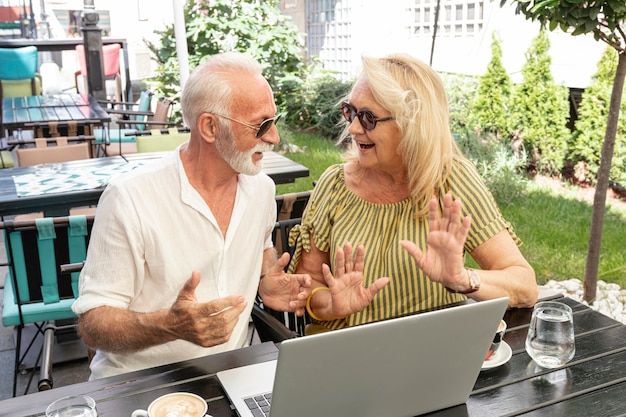 Vieux couple rire ensemble devant un ordinateur portable