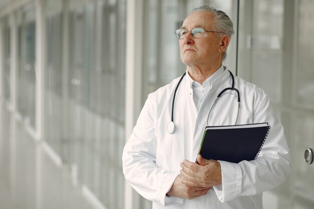 Vieux docteur en uniforme debout dans le hall