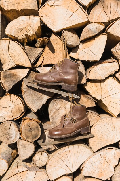 Vieux patins suspendus sur une pile de bois de chauffage