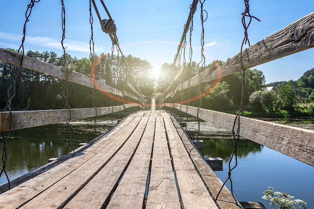 Vieux pont suspendu en bois sur la rivière en journée ensoleillée d'été. paysage naturel. la perspective,,