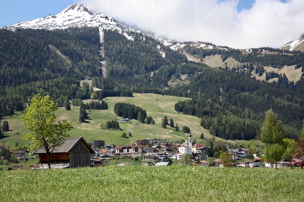Un village avec beaucoup de bâtiments dans un paysage montagneux entouré d'arbres verts
