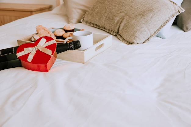 Photo gratuite vin et cadeau près du petit déjeuner sur le lit