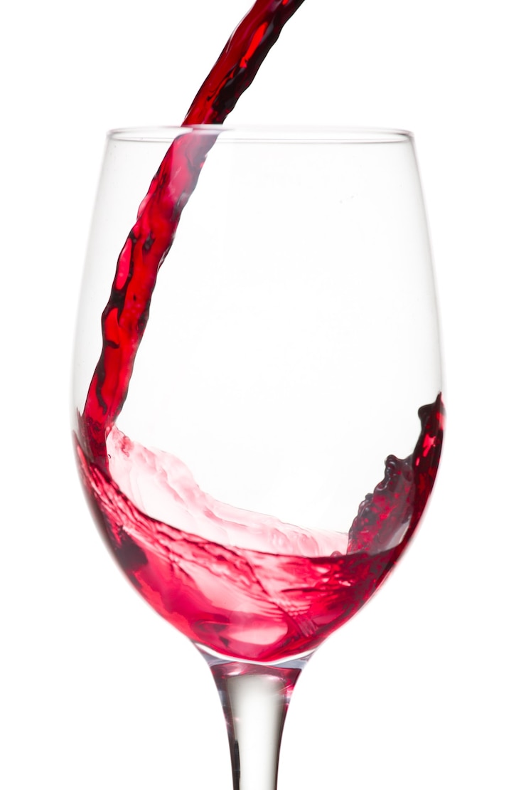 Photo gratuit vin rouge versé dans un verre isolé sur mur blanc