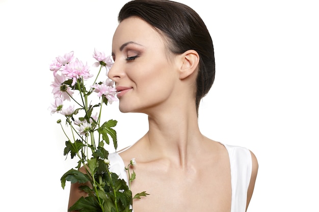 Visage beauté de la belle jeune femme avec des fleurs colorées isolé sur blanc